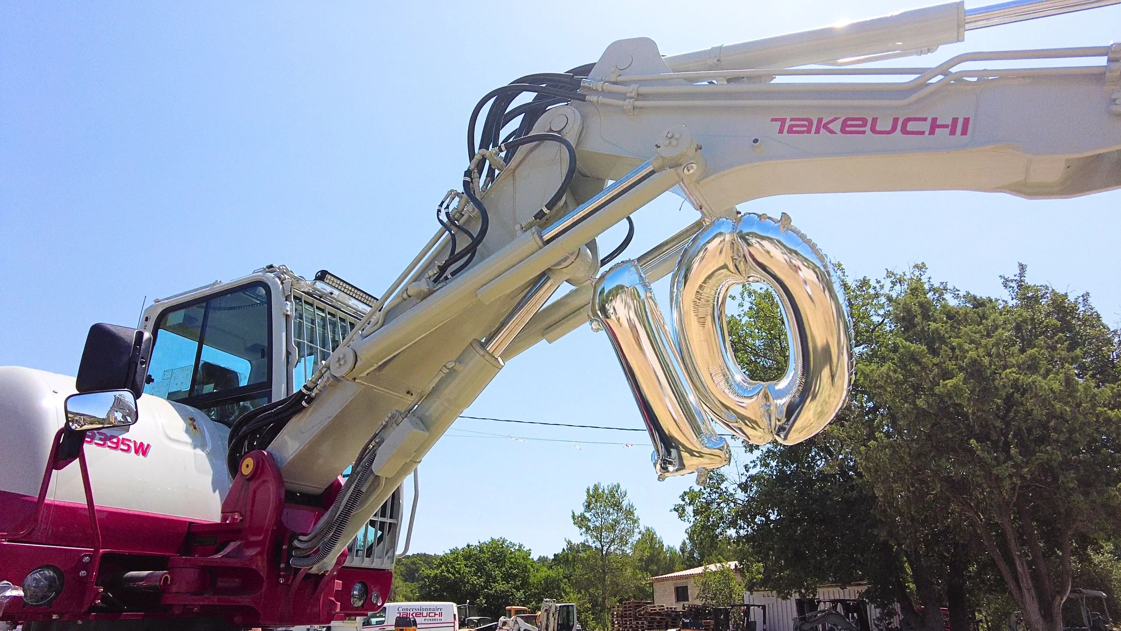 Ballons 10 accrochés sur une pelle Takeuchi afin de célébrer nos 10 ans de partenariat