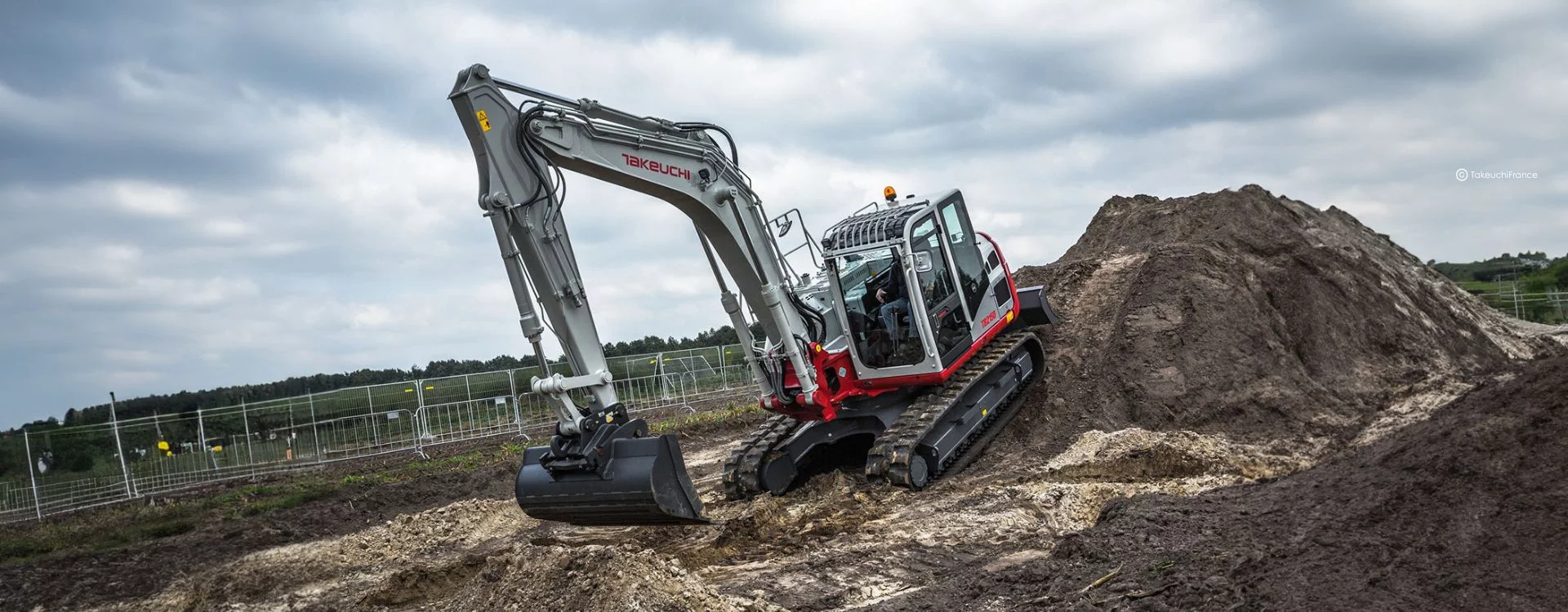 Homme conduisant une pelles hydraulique sur chenille de la marque Takeuchi, modèle TB2150