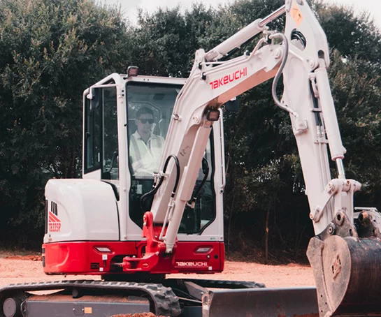 Homme conduisant un modèle de pelle sur chenilles de chez Takeuchi